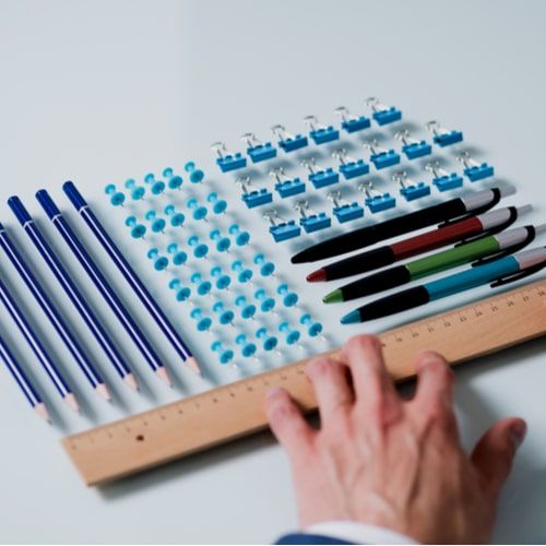 A Person's Hand Arranging Pencils And Multi Colored Pushpins