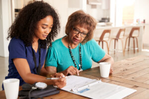 Female Healthcare Worker Filling In A Form With A Senior