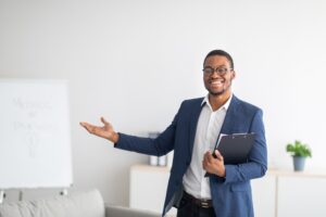 Friendly Young African American Psychologist With Clipboard Showing Something With