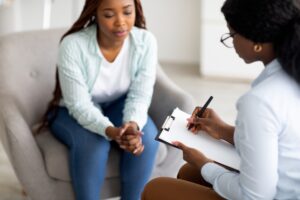 Stressed Black Female Patient Consulting Psychologist At Medical Office Selective