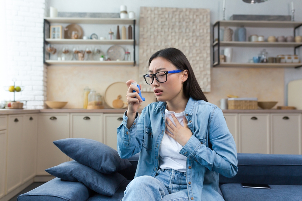 Allergic Attack. Asthma. Young Asian Woman Sitting On Sofa At