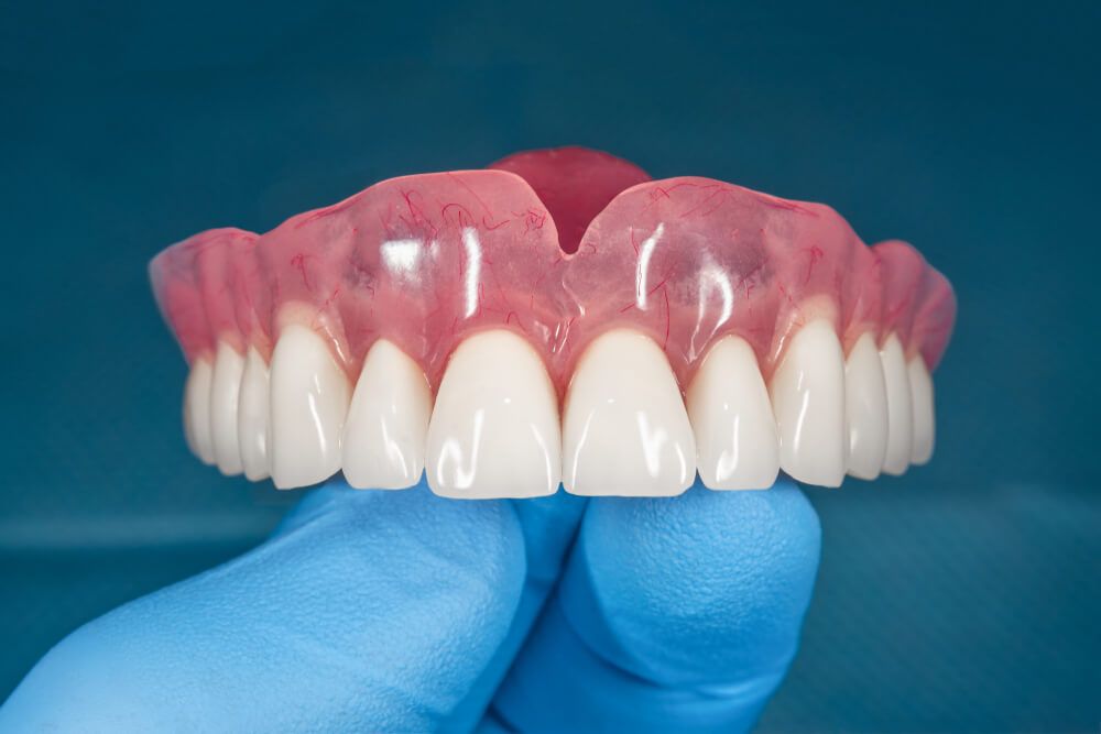 Full removable denture of the upper jaw of man with white beautiful teeth in the hand of a dentist.