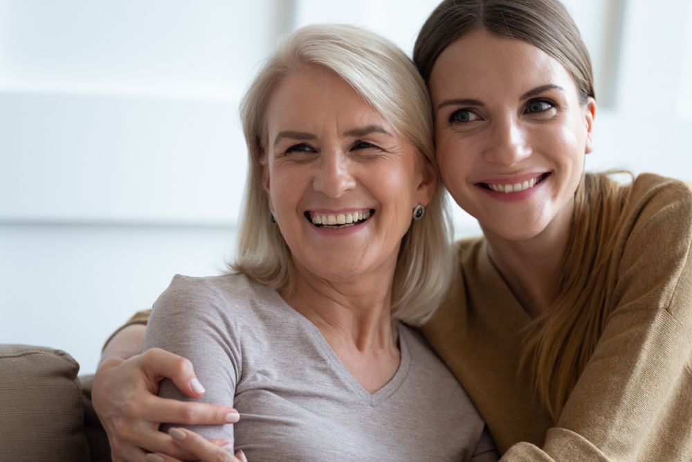 grown up adult 30s daughter embracing elderly blonde mother