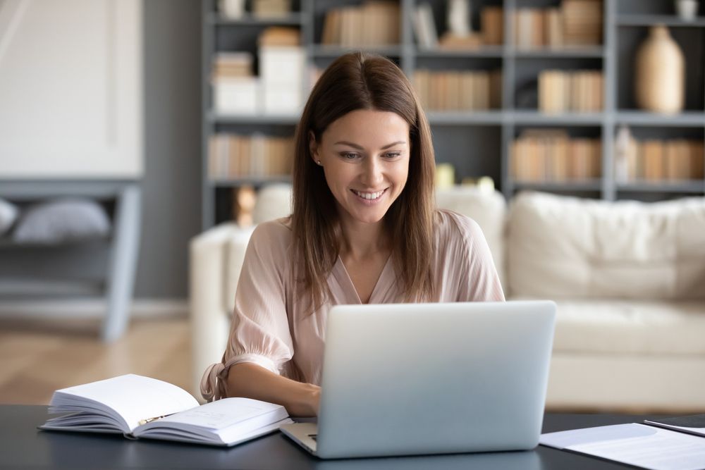 Pleasant attractive smiling lady looking at laptop screen