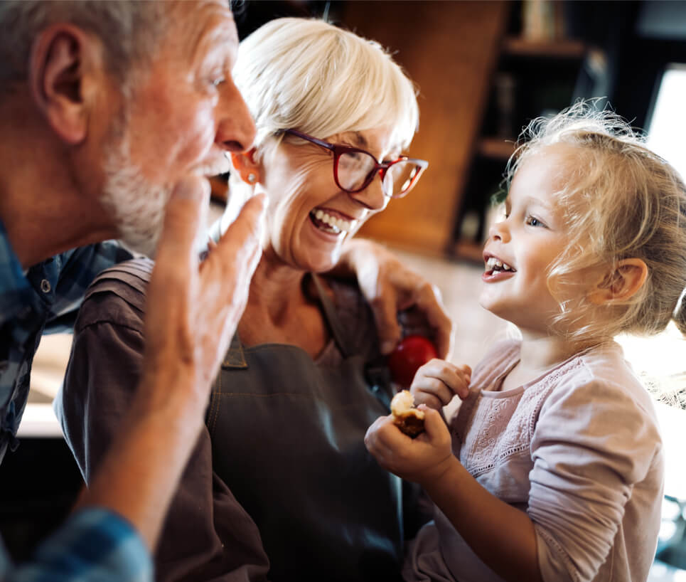 Happy smiling senior grandparents playing with their granddaughter