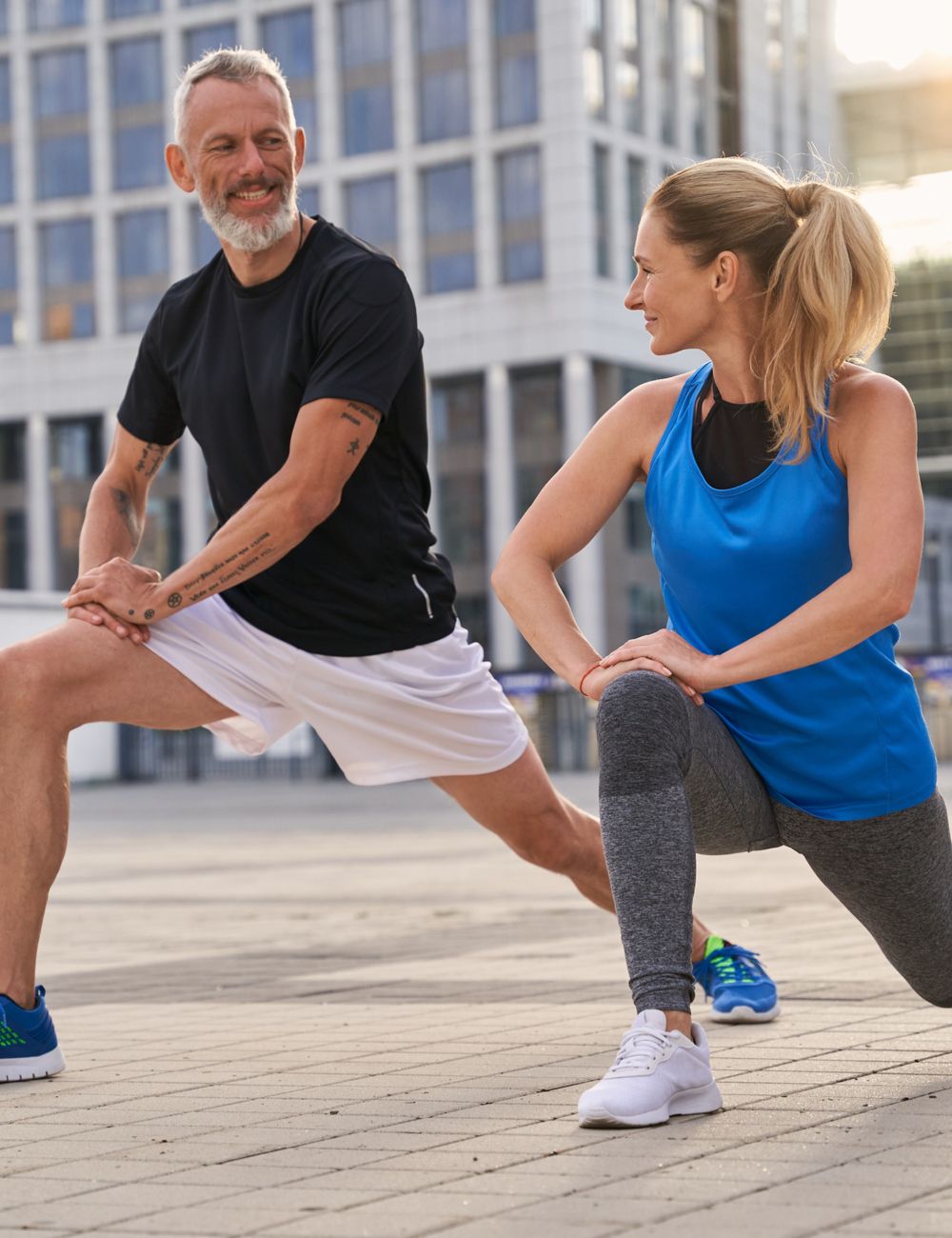 Active sporty middle aged couple, man and woman stretching legs