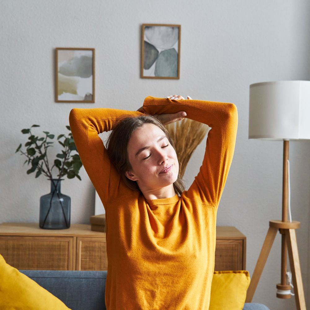 woman stretching arms and relaxing at home sitting in a sofa