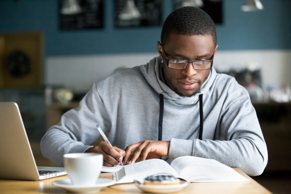 Focused,Millennial,African,American,Student,In,Glasses,Making,Notes,Writing