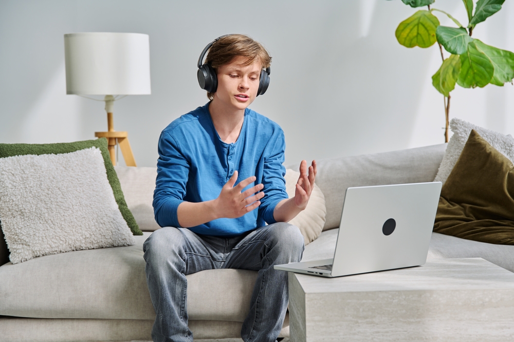 Teenage boy with headphones using laptop for video conference