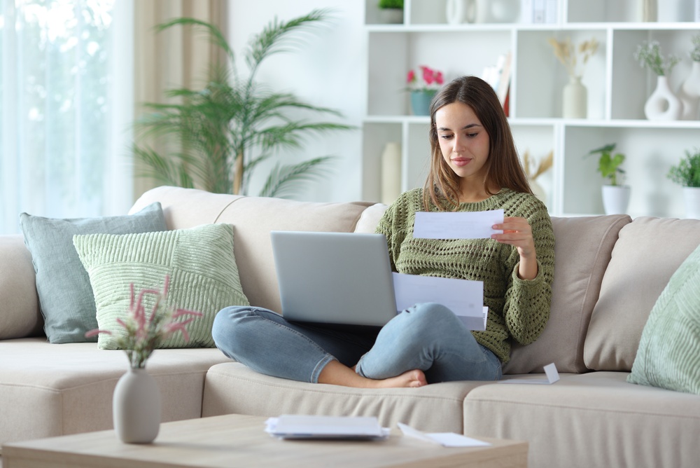 Relaxed woman reading bill doing online accounting with laptop
