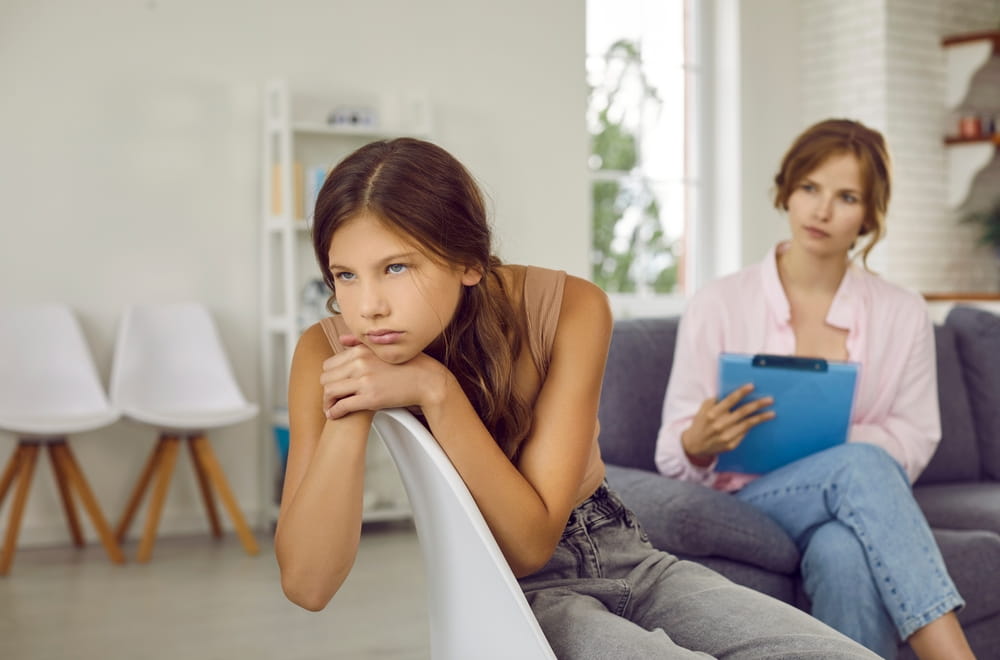 Sad teenage girl does not want to talk about problems and refuses to talk to psychologist.