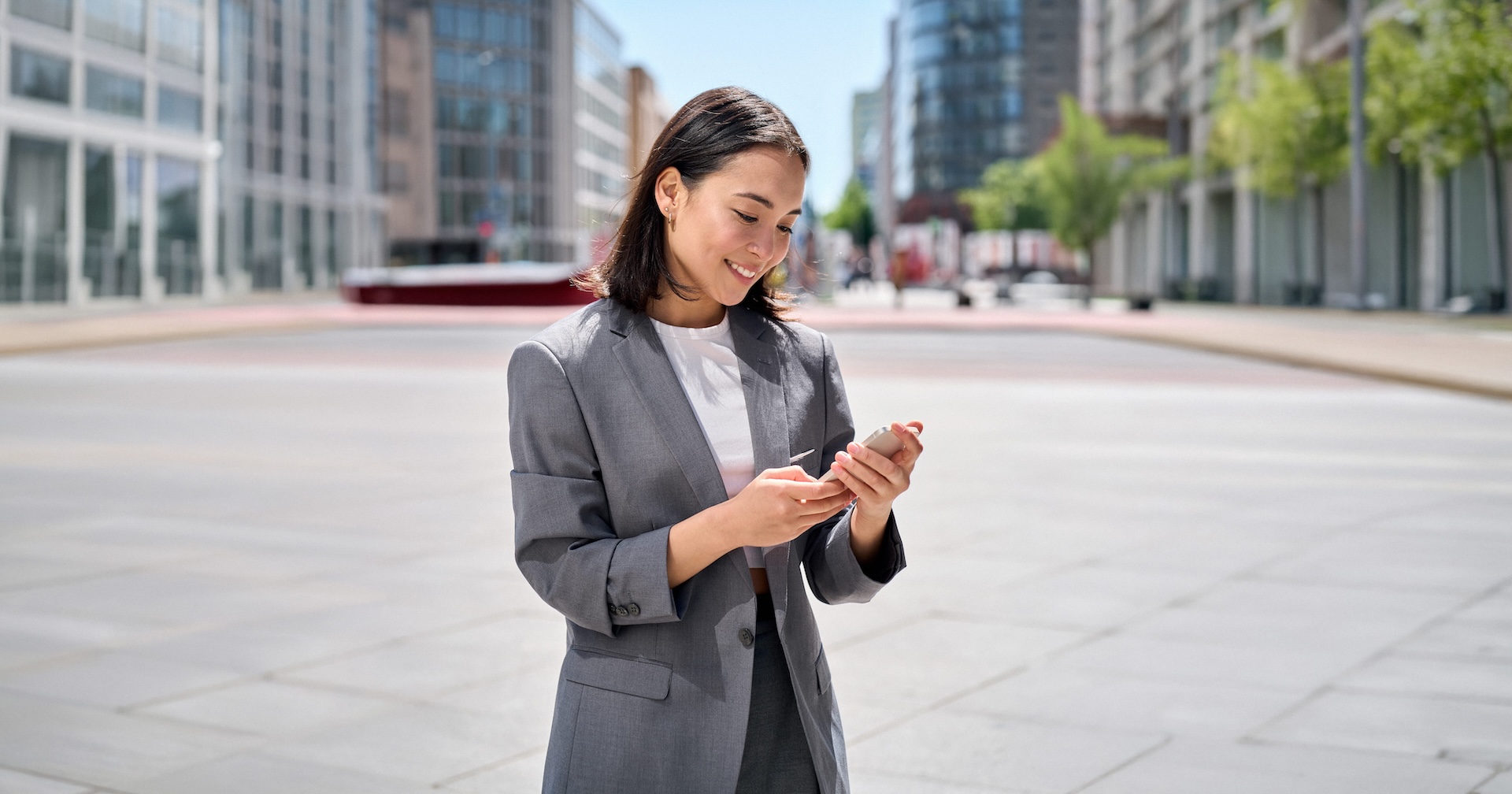 young woman is downtown in professional clothing looking at phone