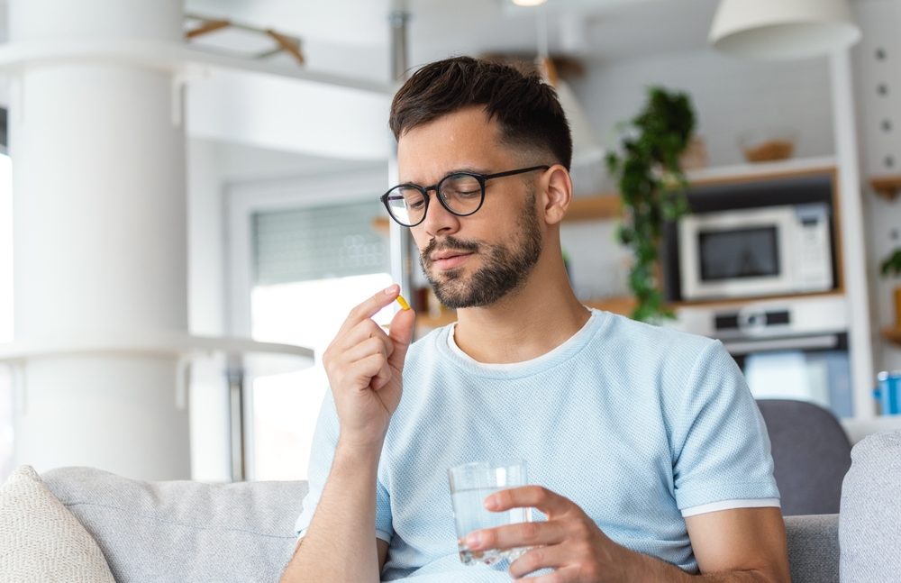 Young man takes medication prescribed by his physician