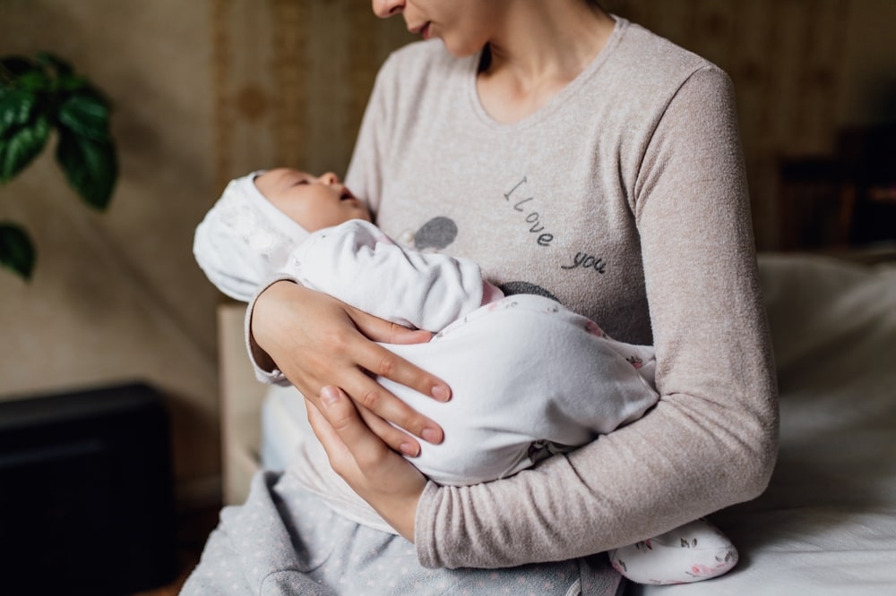 Young mother holding her newborn sleeping baby.