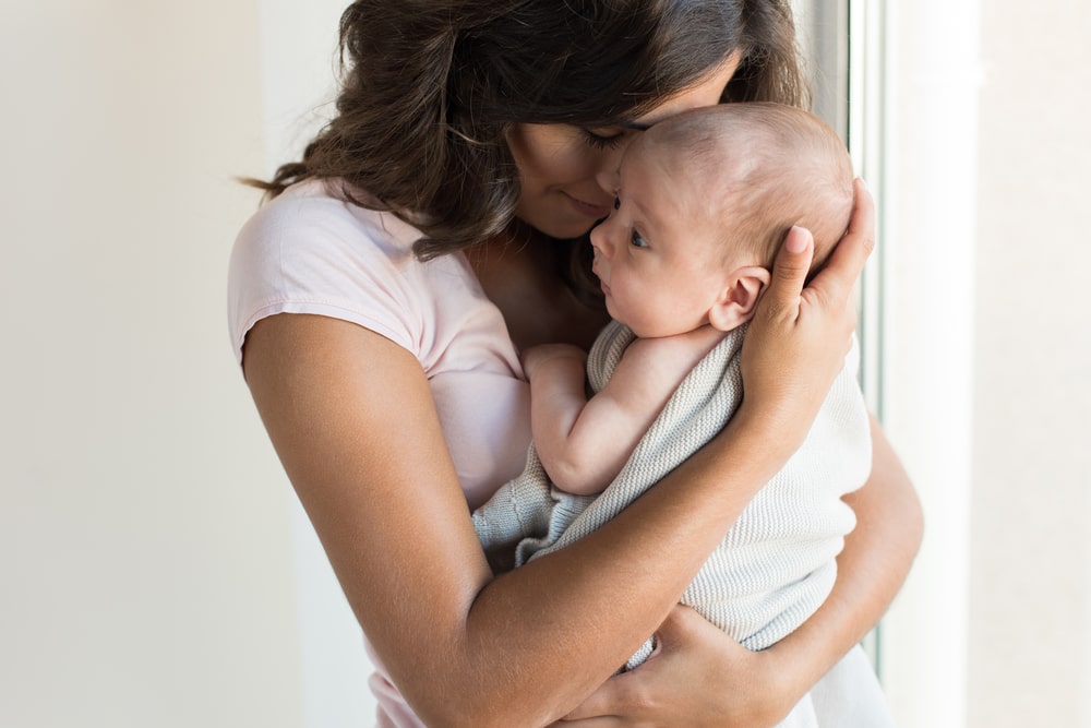 Pretty woman holding a newborn baby in her arms