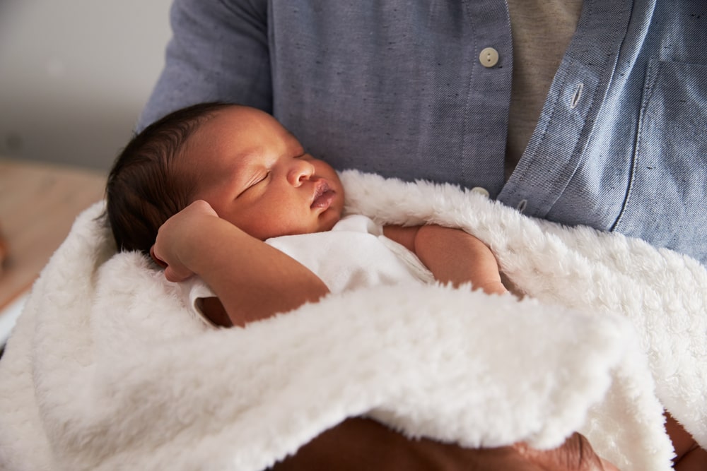 Father Holding Newborn Baby Son In Nursery