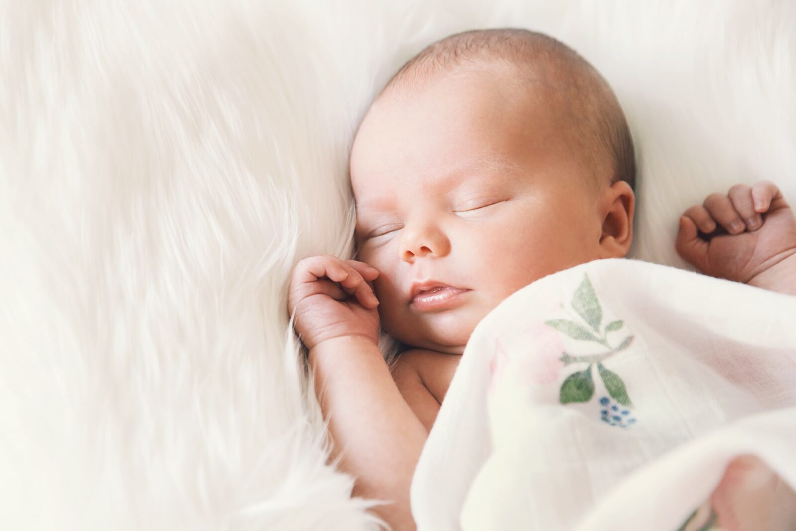 Sleeping newborn baby in a wrap on white blanket