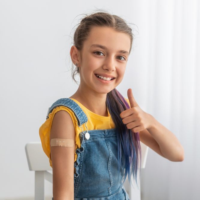 Smiling girl Showing Vaccinated Arm With Sticking Patch On Her Shoulder And Thumb Up Gesture