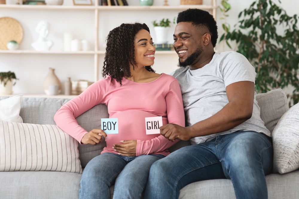 Happy black pregnant couple holding pink and blue color card