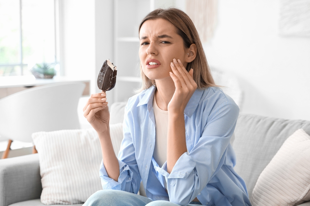 Young woman with cold ice cream suffering from tooth ache at home