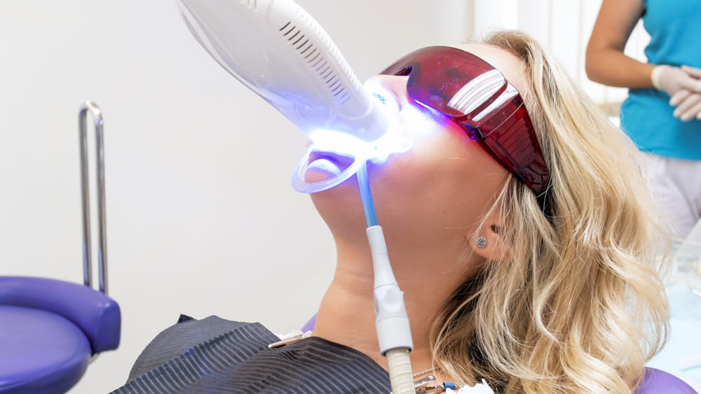 Portrait of young woman visiting dentist office for teeth whitening with photopolymer