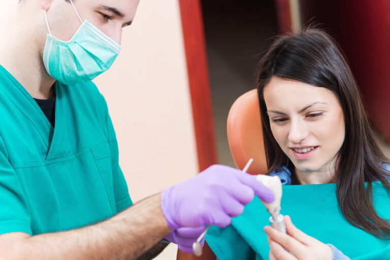 Dentist showing to his patient a dental implant with crown