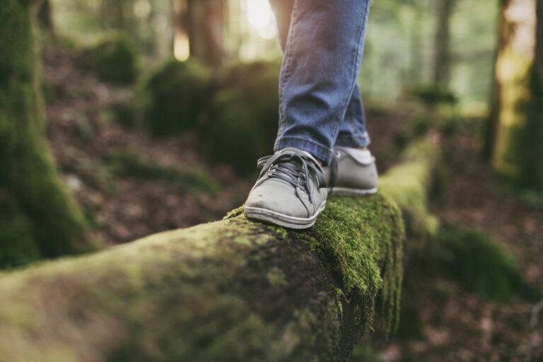 Woman walking on a log in the forest and balancing