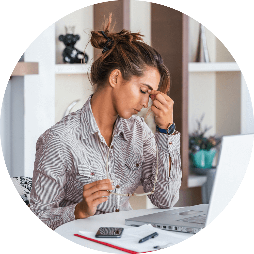 Young frustrated woman working at office desk in front of laptop