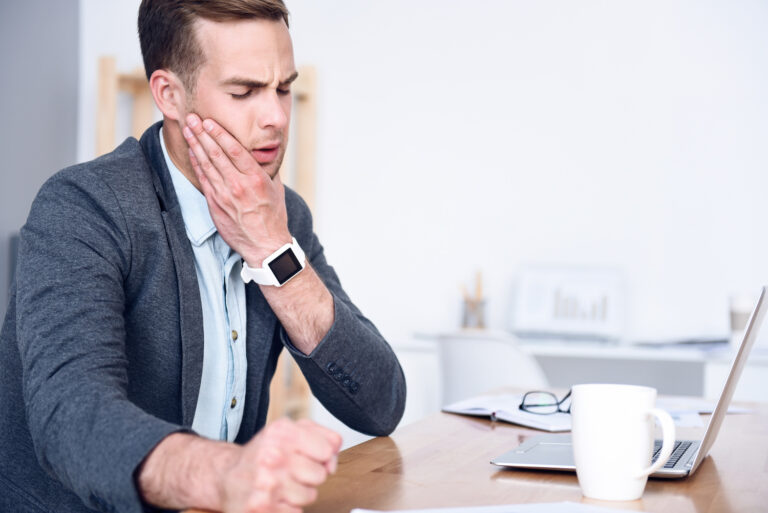 Young man facing tooth pain during work