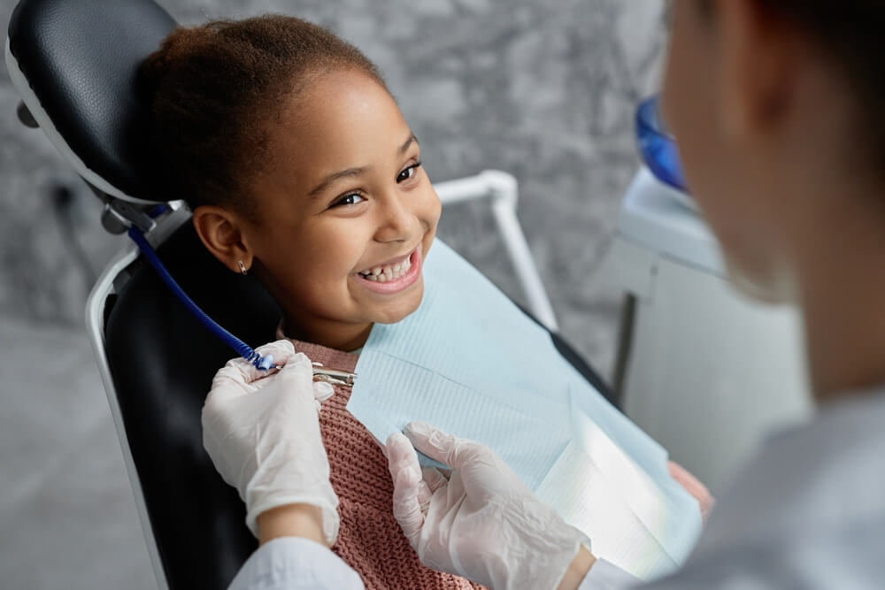 Cute girl in dental chair with nurse or dentist preparing her for teeth exam