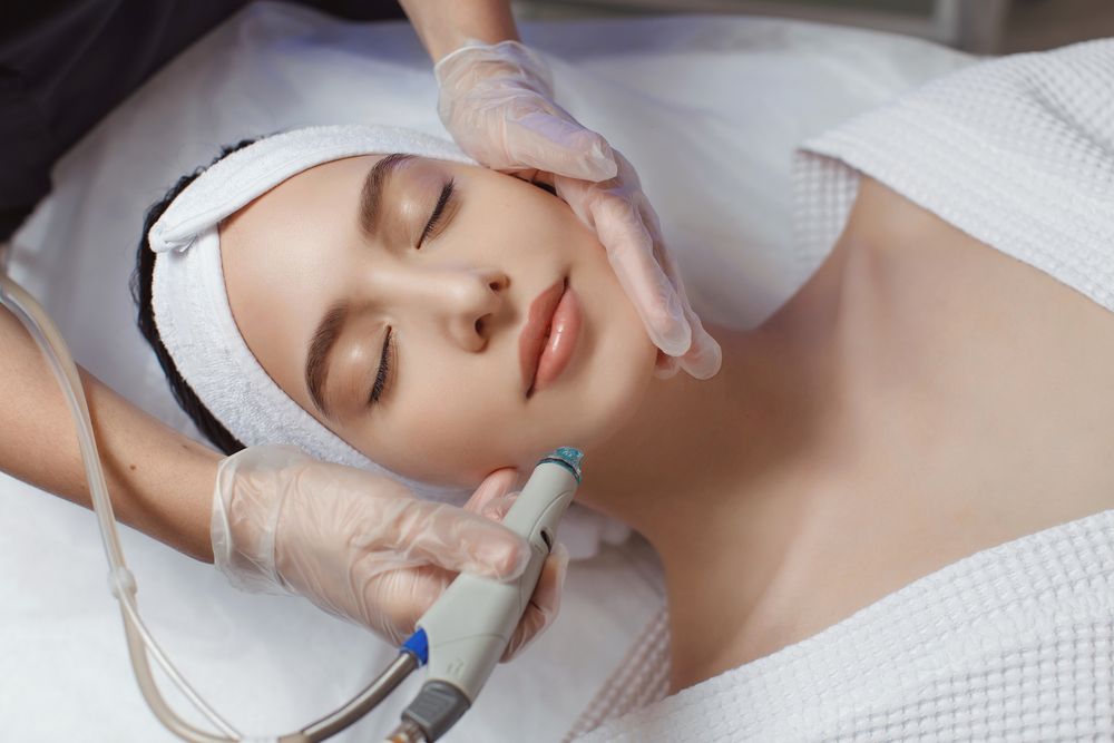Side View Of Woman Receiving Microdermabrasion Therapy On Forehead At