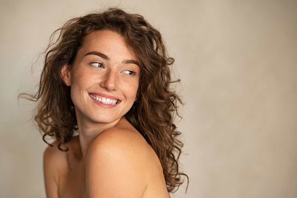 Portrait Of Smiling Girl Enjoying Beauty Treatment On Beige Background.