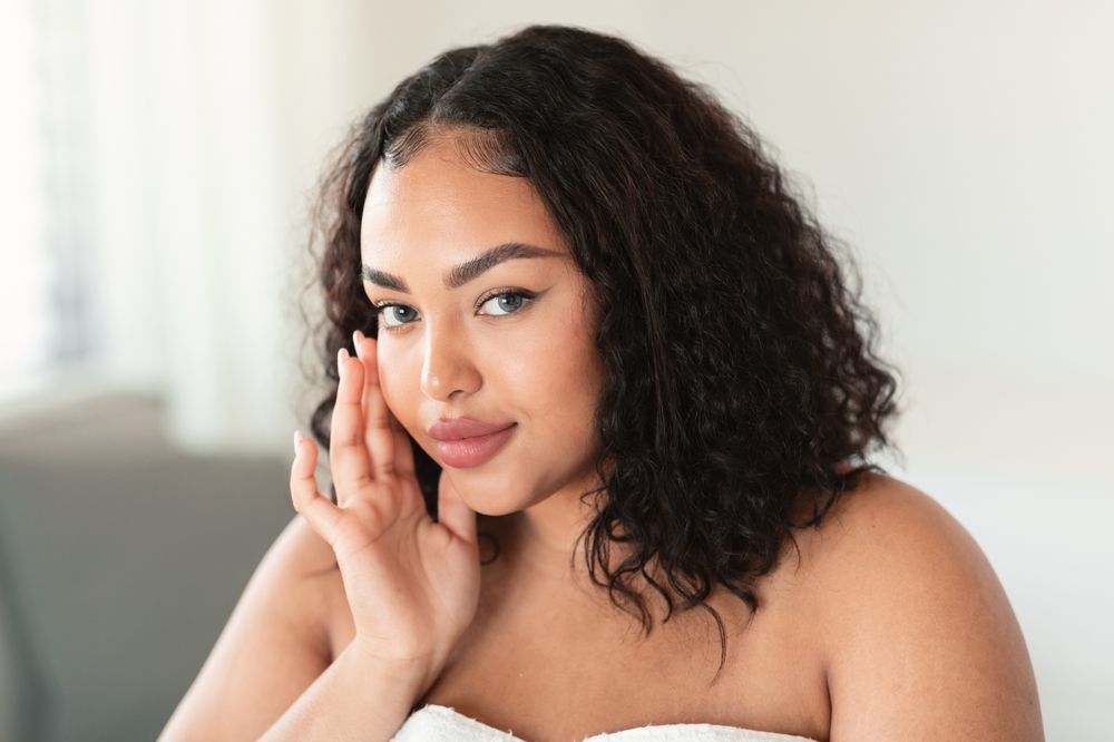 Attractive Black Oversize Woman Touching Face And Looking At Camera