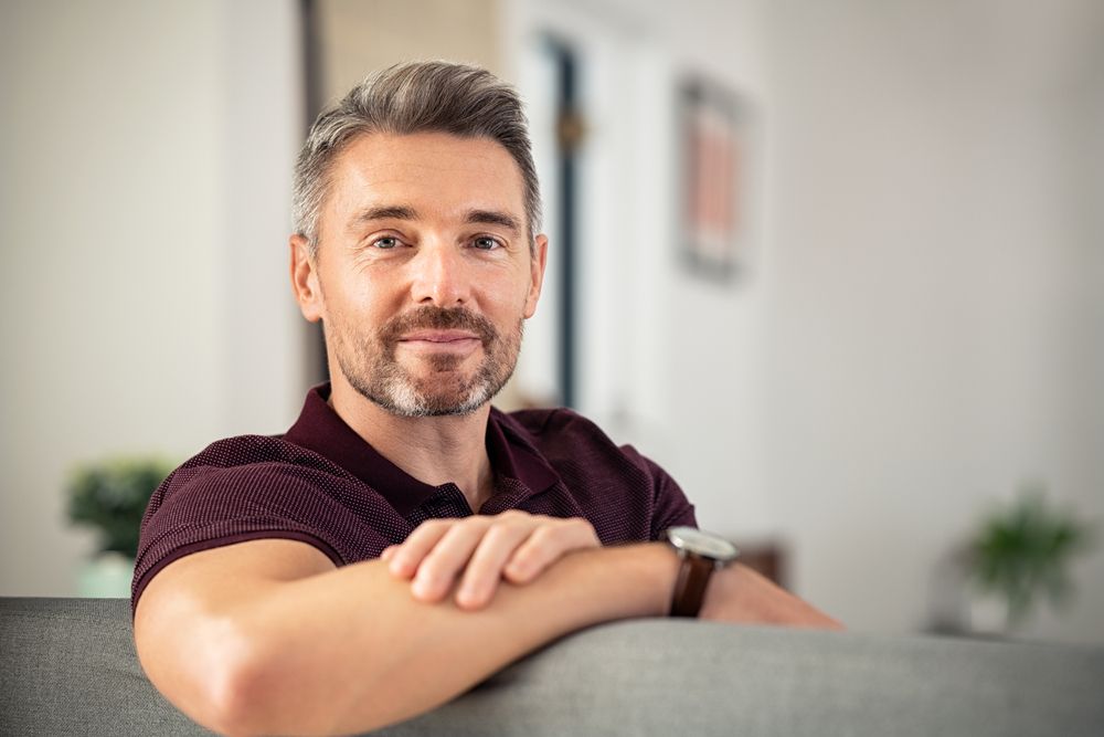 Portrait Of Mature Man Relaxing On Couch At Home While