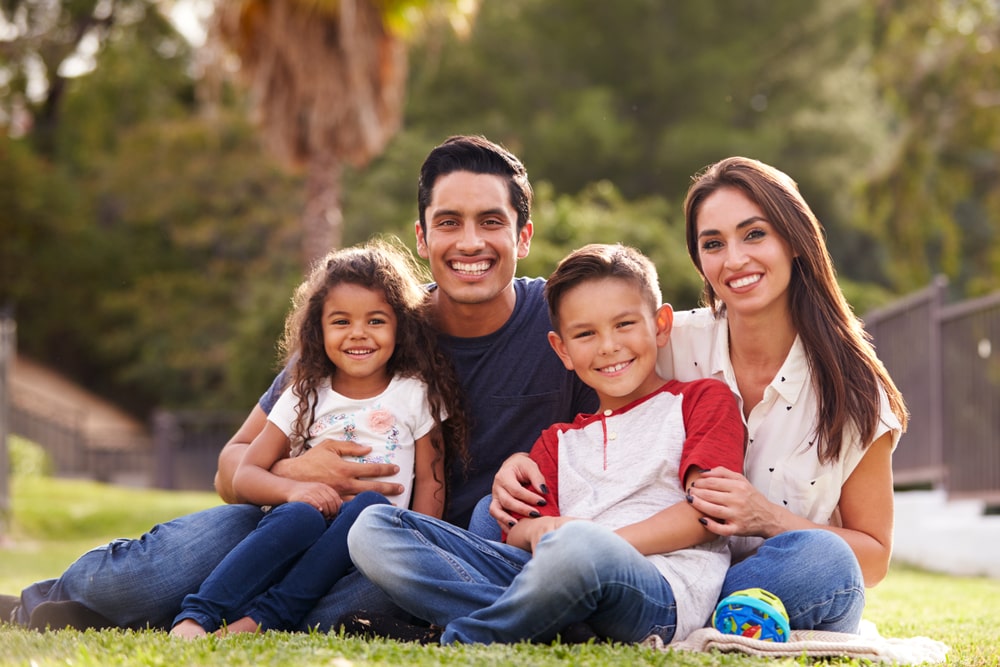 Happy young family sitting the on grass in the park