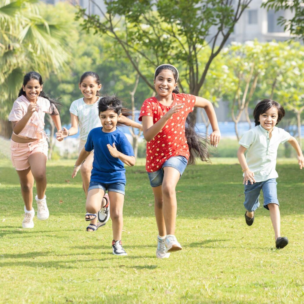 Group of happy playful Indian children running outdoors in spring park