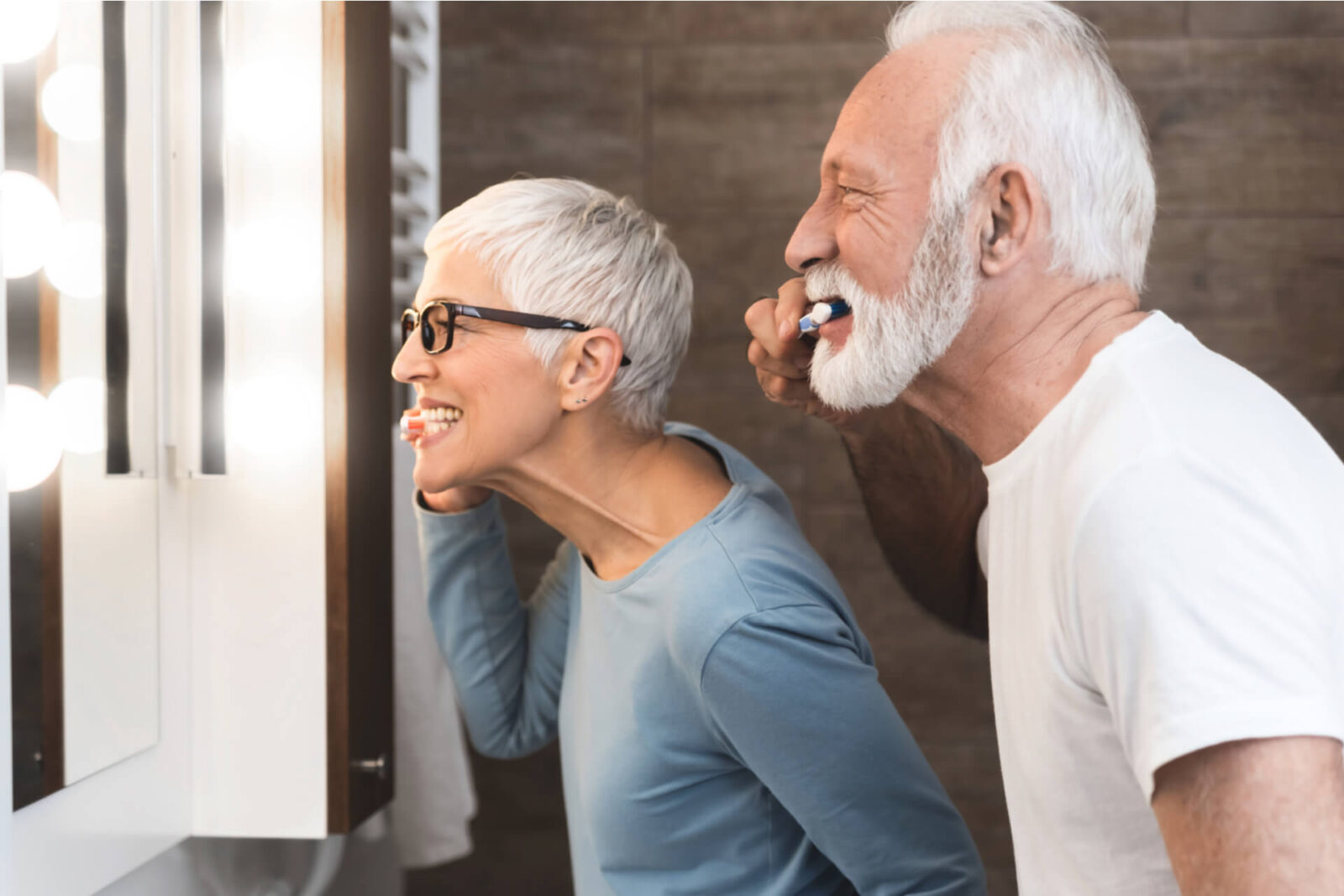 Closeup image of senior couple brushing their teeth together in the bathroom