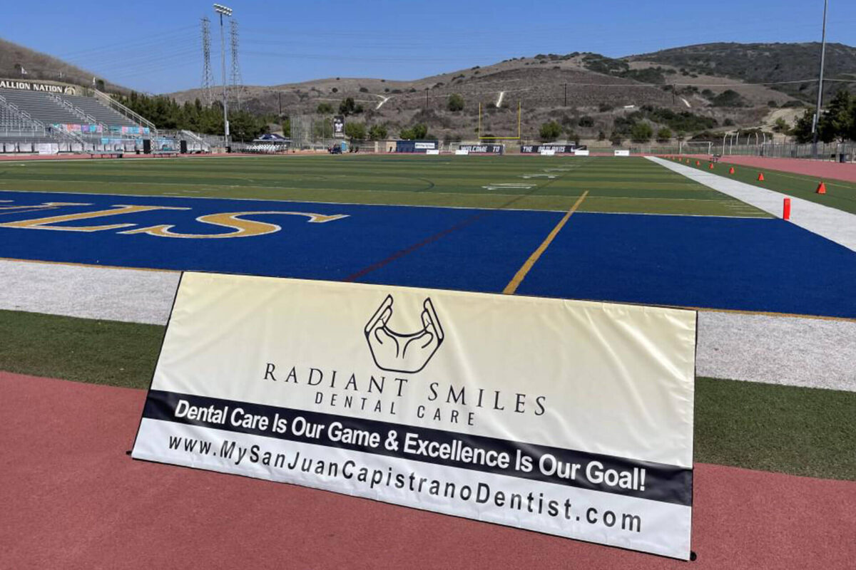 football ground with radient smiles dental care banner