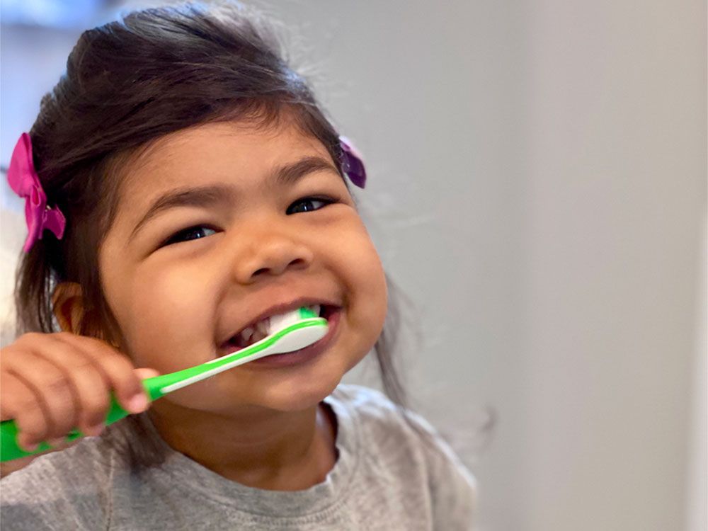 cute girl or kid brushing her teeth by toothbrush