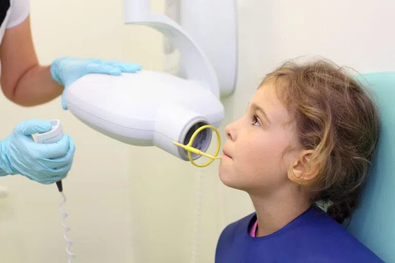 Dentist hands make jaw x-ray image for little girl