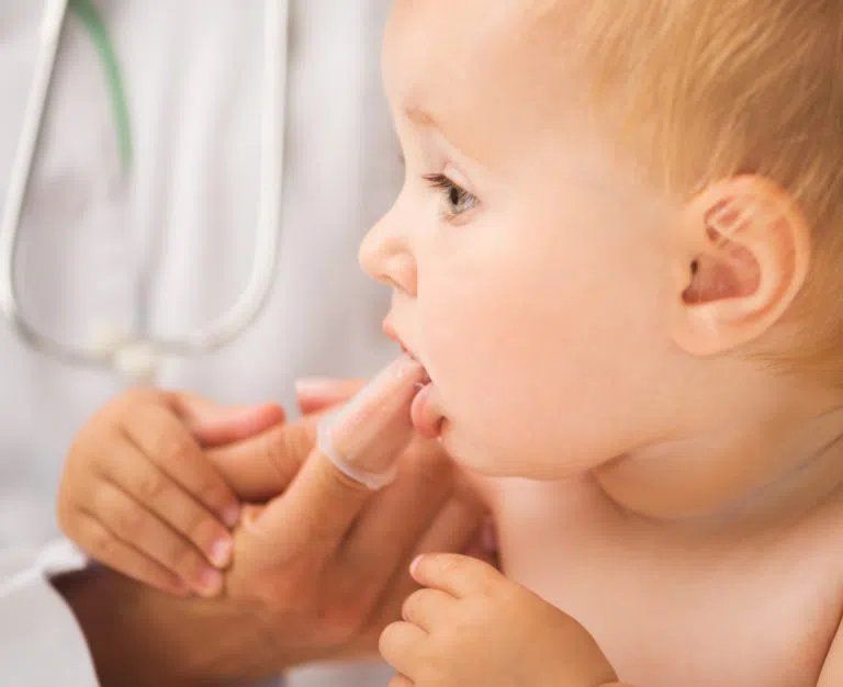 doctor cleaning baby`s mouth with special fingertip
