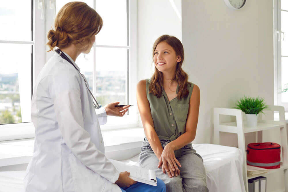 Happy teenage girl is listening to doctor during medical examination