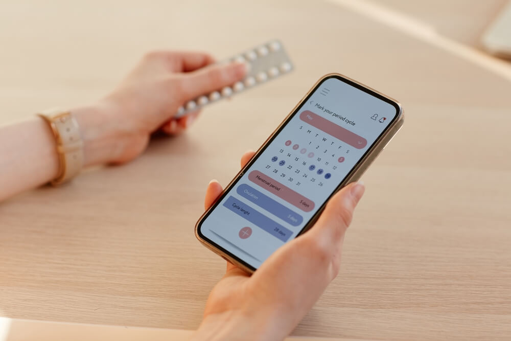 young woman calculating menstrual cycle using mobile app