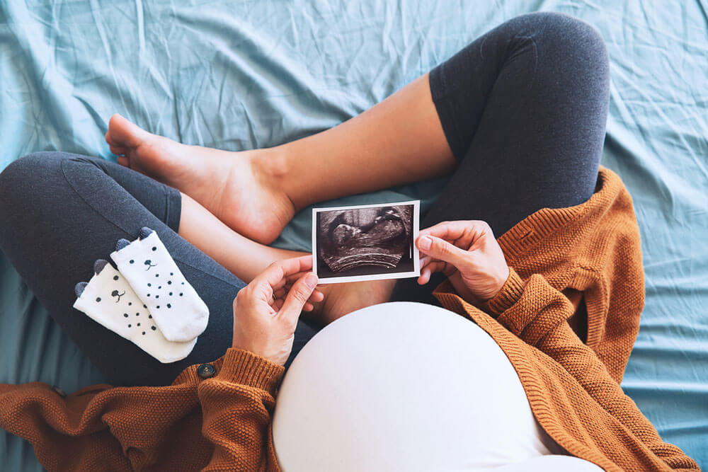 Pregnant woman holding ultrasound image.