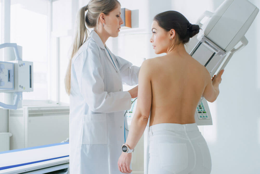 Doctor adjusts Mammogram Machine for a Female Patient.