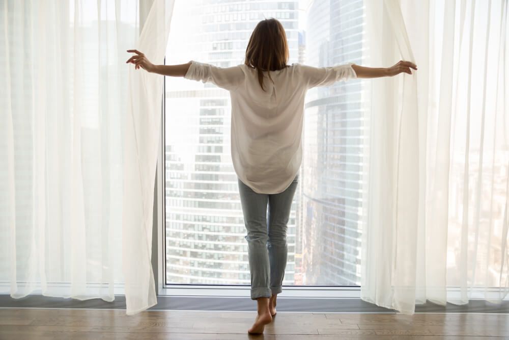 woman standing looking out of full-length window