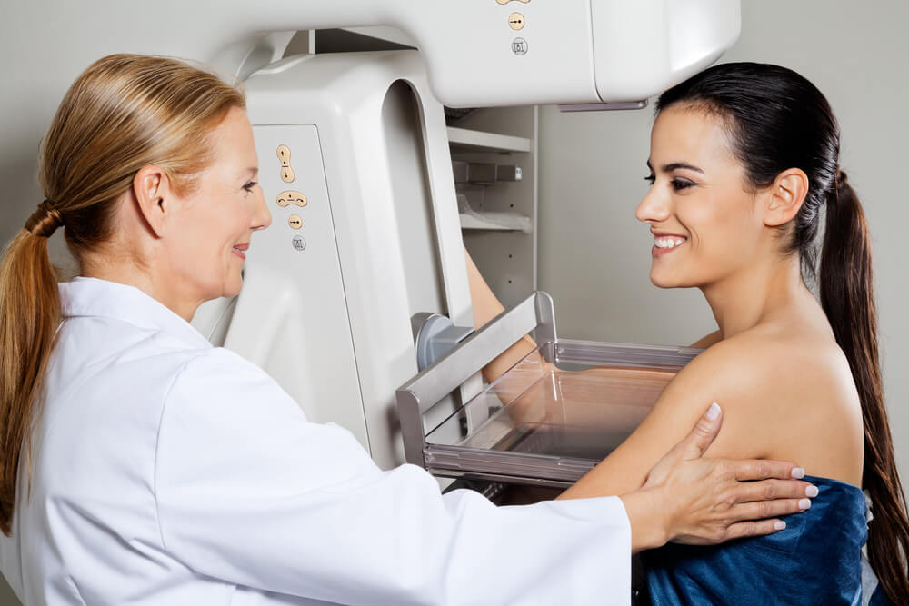 Mature female doctor assisting young patient during mammogram x-ray test