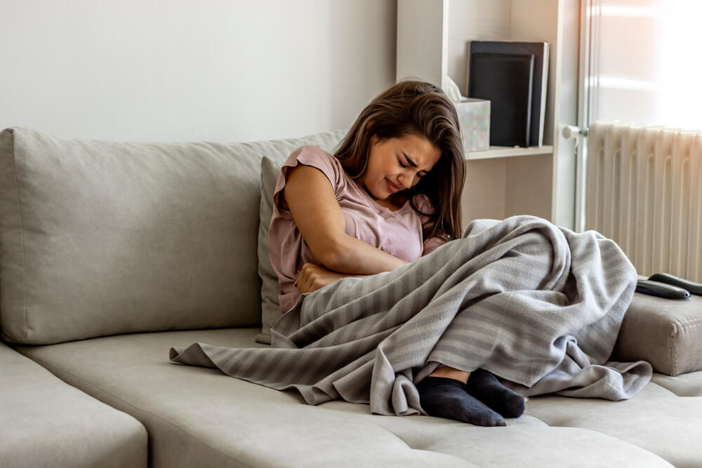 Unhappy woman holding hands on stomach suffering from abdominal pain