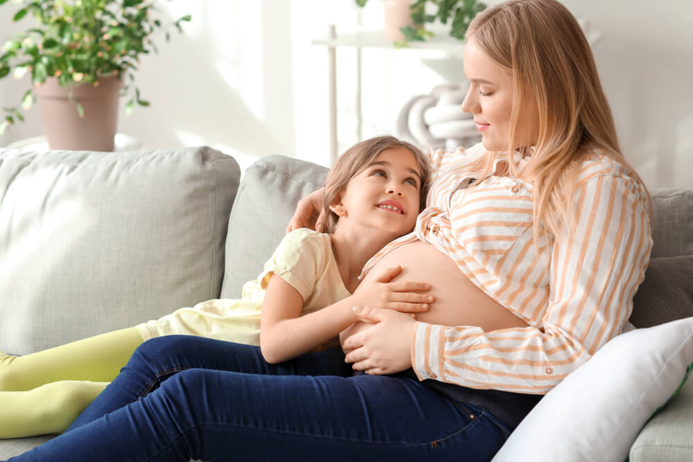 Beautiful pregnant woman with her little daughter at home