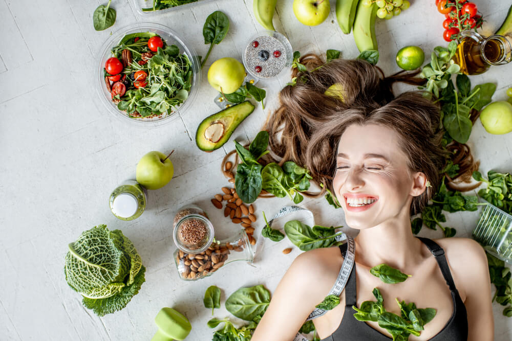 Beauty portrait of a woman surrounded by various healthy food lying on the floor